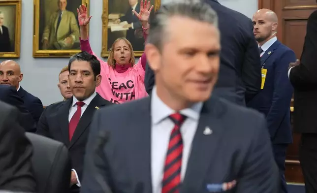 A protester interrupts as Defense Secretary Pete Hegseth arrives to testify at a House Appropriations subcommittee budget hearing for the Department of Defense, Tuesday, May 12, 2026, in Washington. (AP Photo/Alex Brandon)