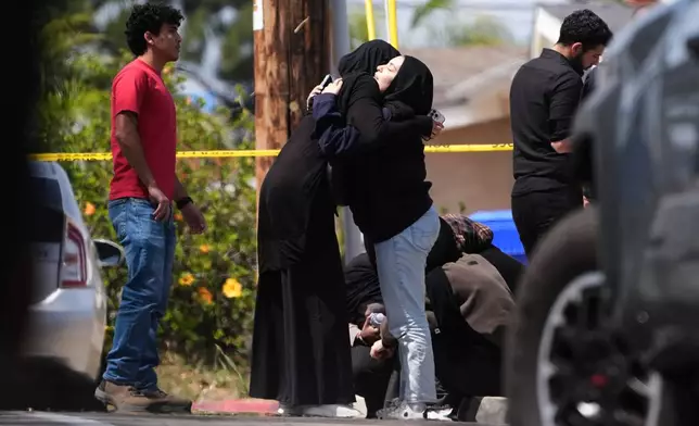 People embrace near the scene of a shooting outside the Islamic Center of San Diego Monday, May 18, 2026, in San Diego. (AP Photo/Gregory Bull)
