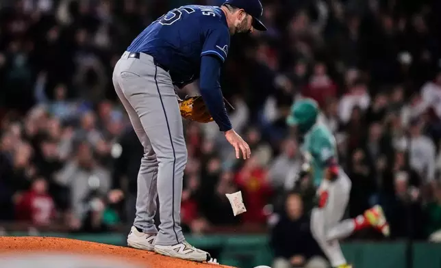 Tampa Bay Rays pitcher Jesse Scholtens drops the rosin bag while preparing a fresh baseball as Boston Red Sox's Ceddanne Rafaela, right, rounds the bases on a solo home run in the fourth inning during a baseball game against the Tampa Bay Rays, Friday, May 8, 2026, in Boston. (AP Photo/Charles Krupa)