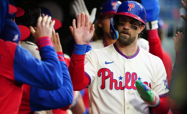 Philadelphia Phillies' Bryce Harper, right, high-fives teammates after scoring on a single hit by Bryson Stott during the fourth inning of a baseball game against the Cleveland Guardians, Saturday, May 23, 2026, in Philadelphia. (AP Photo/Derik Hamilton)
