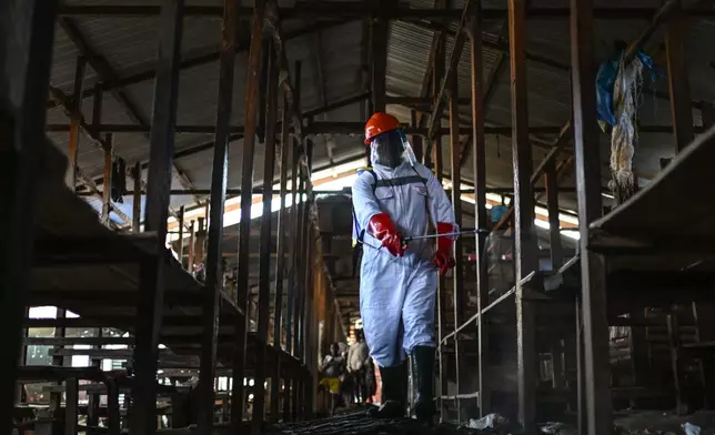 A sanitation worker from the Bunia city government sprays chlorine to disinfect the central market, as Ituri province continues to combat an Ebola outbreak, in Bunia, Congo, Saturday, May 23, 2026. (AP Photo/Moses Sawasawa)
