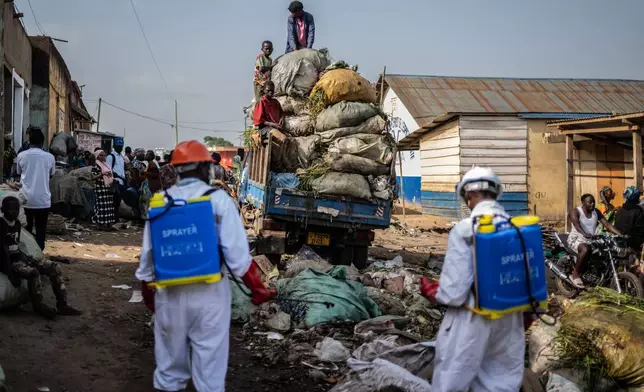 Sanitation workers from Bunia city government spray disinfectant in the central market area near a rubbish truck in Ituri province, as they continue efforts to combat the Ebola outbreak in Bunia, Congo, Saturday, May 23, 2026. (AP Photo/Moses Sawasawa)