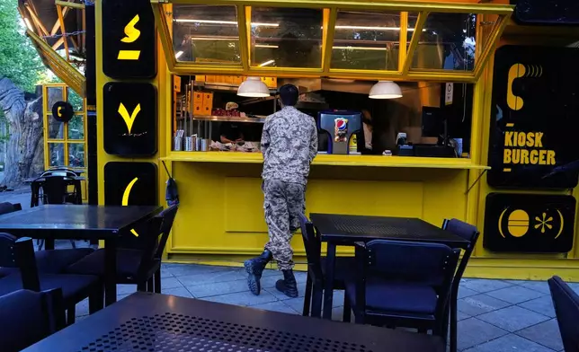 A Revolutionary Guard soldier stands at the counter of a fast food restaurant in northern Tehran, Iran, Sunday, May 10, 2026. (AP Photo/Vahid Salemi)