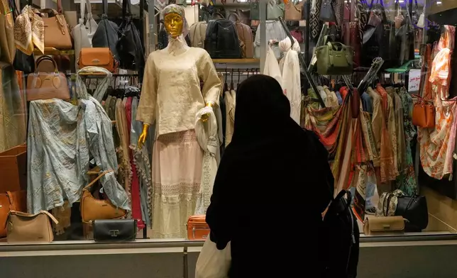 A woman looks at the window display a women's clothing shop in northern Tehran, Iran, Sunday, May 10, 2026. (AP Photo/Vahid Salemi)