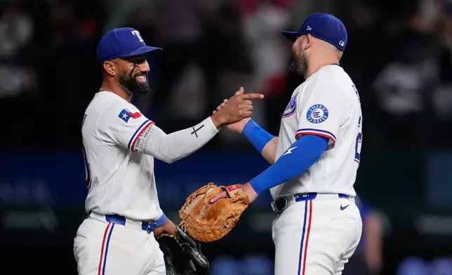 Texas Rangers' Ezequiel Duran, left, and Jake Burger, right, celebrate the team's win in a baseball game against the Arizona Diamondbacks Tuesday, May 12, 2026, in Arlington, Texas. (AP Photo/Tony Gutierrez)