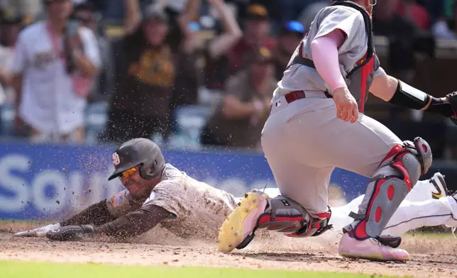San Diego Padres' Nick Castellanos, left, slides in to score from third base off a walk off sacrifice fly by Manny Machado as St. Louis Cardinals catcher Pedro Pagés waits for the throw during the tenth inning of a baseball game Sunday, May 10, 2026, in San Diego. (AP Photo/Gregory Bull)
