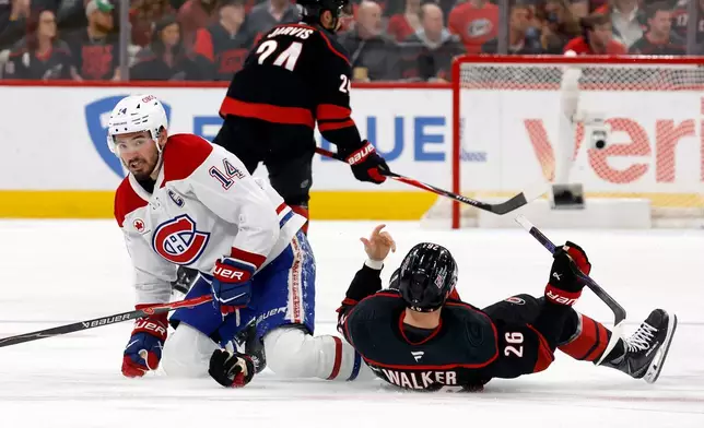 Montréal Canadiens' Nick Suzuki (14) collides with Carolina Hurricanes' Seth Jarvis (24) resulting in both getting penalties during the first period in Game 1 of the Eastern Conference finals NHL hockey Stanley Cup playoffs series in Raleigh, N.C., Thursday, May 21, 2026. (AP Photo/Karl DeBlaker)