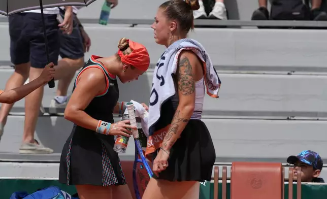 Diana Shnaider of Russia, left, and Oleksandra Oliynykova of Ukraine change sides during their third round women's singles tennis match at the French Open tennis tournament in Paris, Saturday, May 30, 2026. (AP Photo/Thibault Camus)