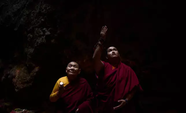 Jalue Dorje, right, looks at a painting inside Maratika Caves, in the Khotang District of eastern Nepal, Monday, April 13, 2026. (AP Photo/Niranjan Shrestha)