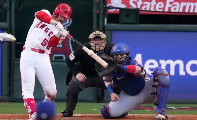 Los Angeles Angels' Wade Meckler, left, hits a three-run home run home plate as umpire Sean Barber, center, and Texas Rangers catcher Danny Jansen watch during the first inning of a baseball game against the Texas Rangers, Friday, May 22, 2026, in Anaheim, Calif. (AP Photo/Mark J. Terrill)