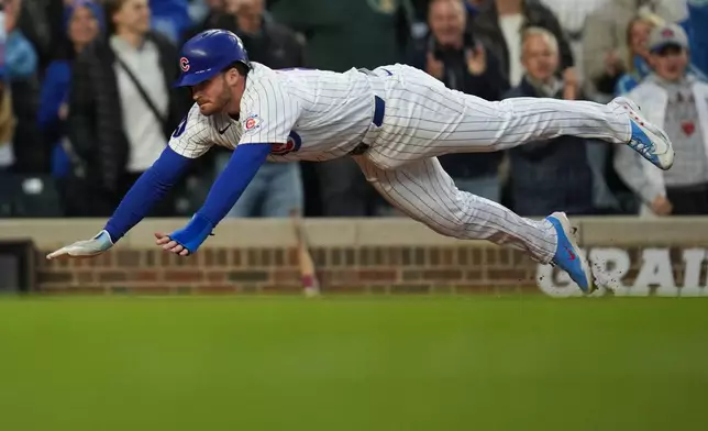 Chicago Cubs' Ian Happ (8) dives into home to score on a double from Seiya Suzuki (27) during the fourth inning of a baseball game against the Cincinnati Reds, Wednesday, May 6, 2026, in Chicago. (AP Photo/Erin Hooley)