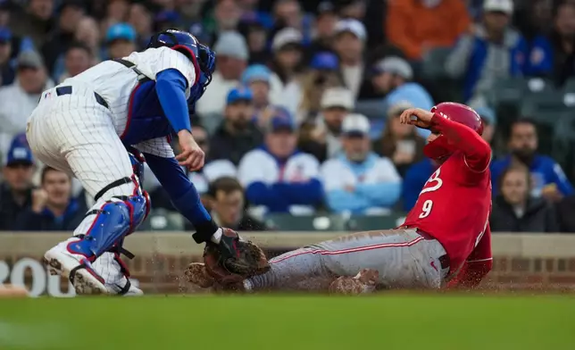 Chicago Cubs catcher Carson Kelly, left, tags out Cincinnati Reds' Matt McLain (9) at home during the third inning of a baseball game, Wednesday, May 6, 2026, in Chicago. (AP Photo/Erin Hooley)