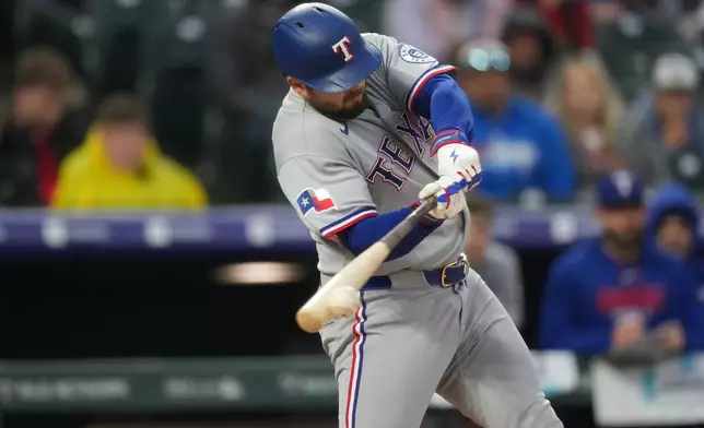 Texas Rangers' Jake Burger connects for an RBI single off Colorado Rockies relief pitcher Tanner Gordon in the second inning of a baseball game Tuesday, May 19, 2026, in Denver. (AP Photo/David Zalubowski)