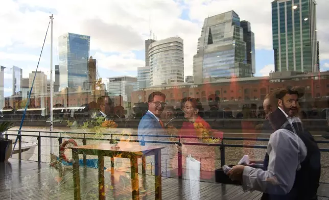 Guests are reflected in a window during a ceremony organized by the Dutch embassy for King's Day in Buenos Aires, Argentina, Monday, April 27, 2026. (AP Photo/Rodrigo Abd)