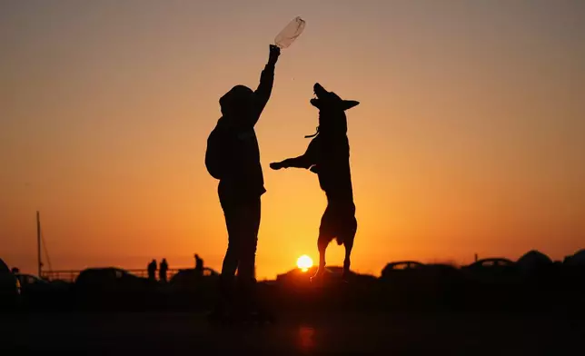 Sidra Mohamad Saadeh, 13, who was displaced by Israeli airstrikes in Dahiyeh, Beirut's southern suburbs, plays with a dog named Rocky in a public space along the Beirut waterfront at sunset in Beirut, Lebanon, Wednesday, April 29, 2026. (AP Photo/Hassan Ammar)