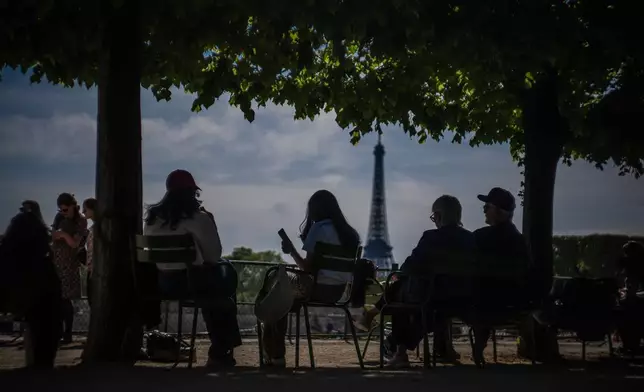 People relax in the Tuileries Garden in front of the Eiffel Tower in Paris, Saturday, April 25, 2026 in Paris. (AP Photo/Aurelien Morissard)