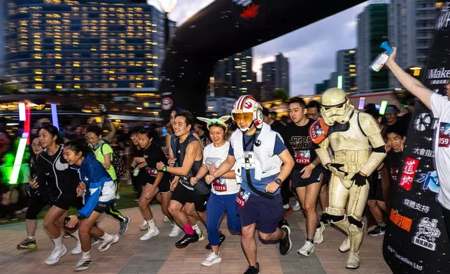 Star Wars fans, some dressed in costumes, run along Victoria Harbour during a themed night run in Hong Kong, Friday, May 1, 2026. (AP Photo/Chan Long Hei)