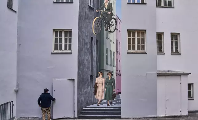 A man walks through a courtyard featuring a mural in central Warsaw, Poland, Friday, April 24, 2026. (AP Photo/Ebrahim Noroozi)