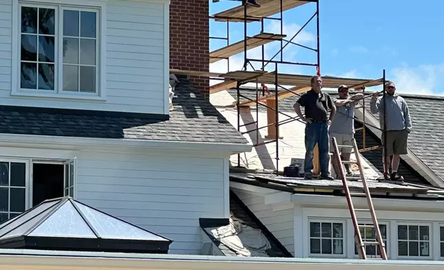 Construction workers watch the PGA Championship golf tournament from the roof of a home outside Aronimink Golf Club, Friday, May 15, 2026 in Newtown Square, Pa. (AP Photo/Dan Gelston)