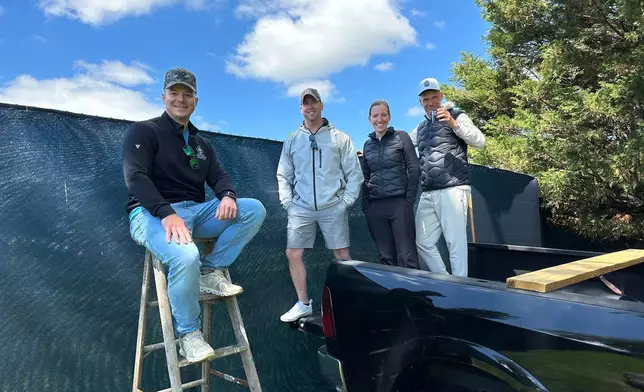 Golf fans pose for a photo while watching the PGA Championship golf tournament from pickup trucks and ladders from neighborhood homes outside Aronimink Golf Club, Friday, May 15, 2026 in Newtown Square, Pa. (AP Photo/Dan Gelston)