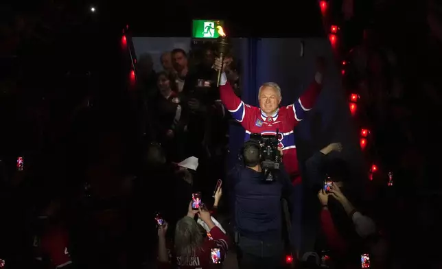 FILE - Former Montreal Canadiens player Claude Lemieux holds a torch as he enters the arena before Game 3 of the NHL Eastern Conference final Stanley Cup playoff series between the Canadiens and Carolina Hurricanes, Monday, May 25, 2026, in Montreal. (Christinne Muschi/The Canadian Press via AP, File)