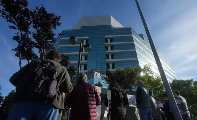 An interfaith community group holds signs while singing outside of Immigration Court Tuesday, May 12, 2026, in Concord, Calif. (AP Photo/Jeff Chiu)