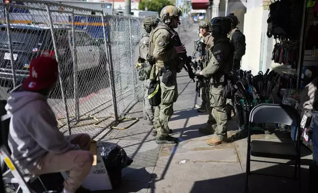 Law enforcement officers stand on a street near MacArthur Park after federal authorities made arrests on charges related to selling illicit drugs on Wednesday, May 6, 2026, in Los Angeles. (AP Photo/Jae C. Hong)