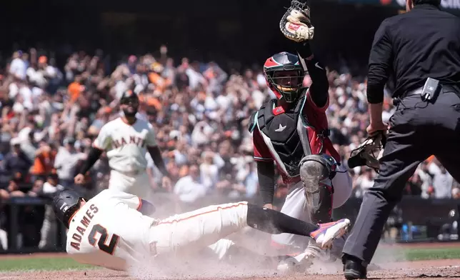 Arizona Diamondbacks catcher Aramis Garcia, middle right, reacts after tagging out San Francisco Giants' Willy Adames (2) at home during the eighth inning of a baseball game Wednesday, May 27, 2026, in San Francisco. (AP Photo/Jeff Chiu)