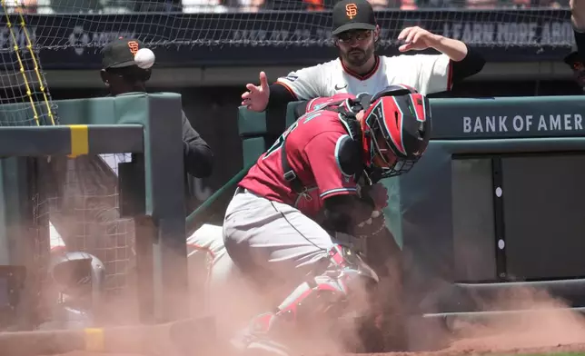San Francisco Giants infield coach Ron Washington, top left, and manager Tony Vitello, top right, watch as Arizona Diamondbacks catcher Aramis Garcia, bottom, cannot catch a ball in foul territory hit by Will Brennan during the fifth inning of a baseball game Wednesday, May 27, 2026, in San Francisco. (AP Photo/Jeff Chiu)