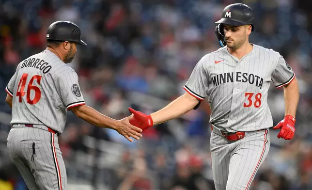 Minnesota Twins' Matt Wallner (38) celebrates his home run with third base coach Ramon Borrego (46) during the fifth inning of a baseball game against the Washington Nationals, Wednesday, May 6, 2026, in Washington. (AP Photo/Nick Wass)