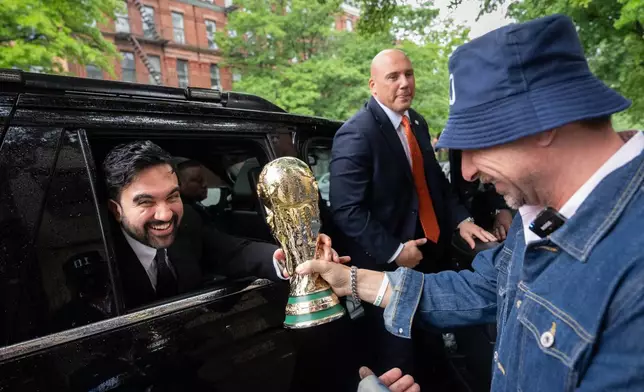 New York Mayor Zohran Mamdani is passed a replica World Cup Trophy by Ezequiel Cecchi, 49, after making a World Cup soccer tournament announcement at Harlem Tavern, Thursday, May 21, 2026 in New York. (AP Photo/Adam Gray)