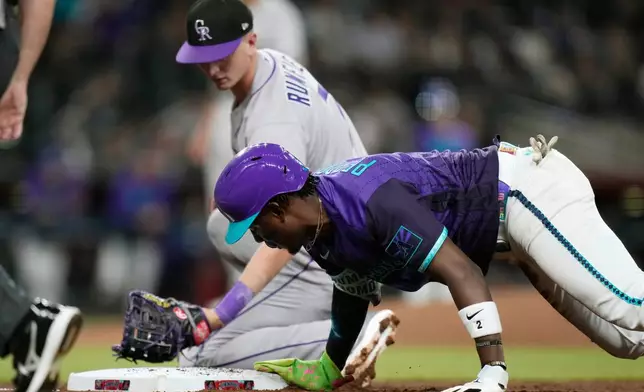 Arizona Diamondbacks' Geraldo Perdomo, right, dives safely back to first base as Colorado Rockies first baseman TJ Rumfield (7) applies a late pickoff tag during the fourth inning of a baseball game, Friday, May 22, 2026, in Phoenix. (AP Photo/Ross D. Franklin)