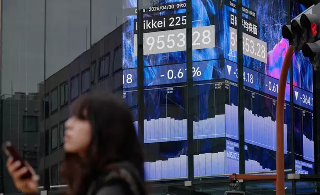 A person stands in front of an electronic stock board showing Japan's Nikkei index at a securities firm Thursday, April 30, 2026, in Tokyo. (AP Photo/Eugene Hoshiko)