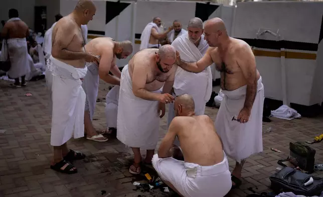 Muslim pilgrims shave each other's heads, during a ritual known as "halq," marking the completion of Hajj after the symbolic stoning of the devil in Mina near the holy city of Mecca, Saudi Arabia, Wednesday, May 27, 2026. (AP Photo/Altaf Qadri)