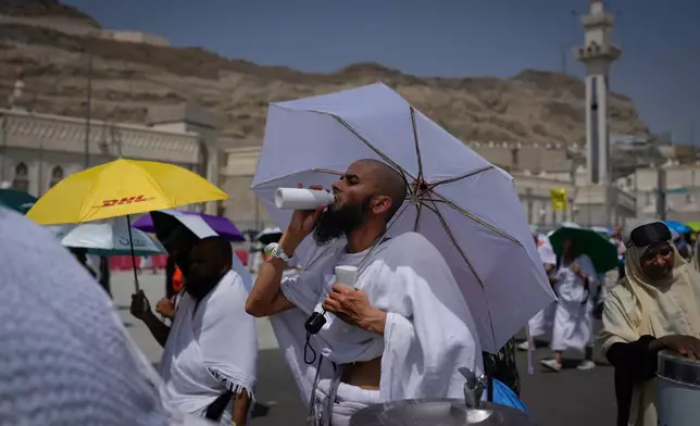 A Muslim pilgrim drinks water as pilgrims walk on their way to cast pebbles at pillars in the symbolic stoning of the devil, the last rite of the annual Hajj, in Mina near the holy city of Mecca, Saudi Arabia, Wednesday, May 27, 2026. (AP Photo/Altaf Qadri)