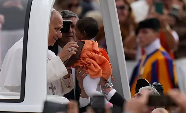 Pope Leo XIV blesses a little girl as he arrives for his weekly general audience in St. Peter's Square, at the Vatican, Wednesday, May 13, 2026. (AP Photo/Alessandra Tarantino)