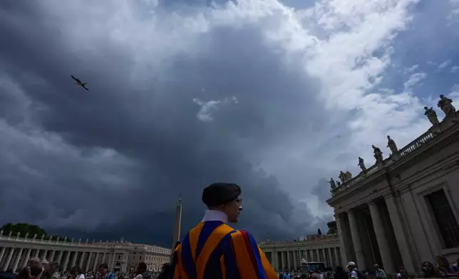 A Swiss Guard stands as dark clouds hang over, during Pope Leo XIV's weekly general audience in St. Peter's Square, at the Vatican, Wednesday, May 13, 2026. (AP Photo/Alessandra Tarantino)
