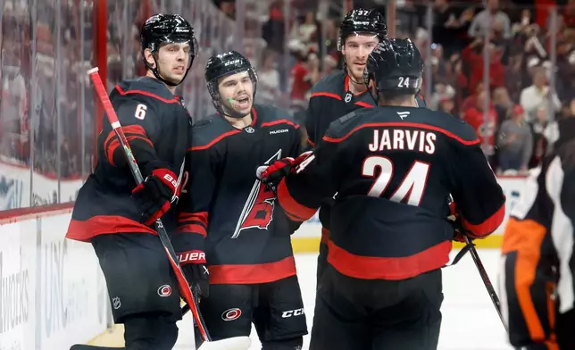 Carolina Hurricanes' Logan Stankoven (22) celebrates after his second goal with teammates Mike Reilly (6), Andrei Svechnikov, back right, and Seth Jarvis (24) during the second period of Game 1 of an NHL hockey Stanley Cup second-round playoff series against the Philadelphia Flyers in Raleigh, N.C., Saturday, May 2, 2026. (AP Photo/Karl DeBlaker)