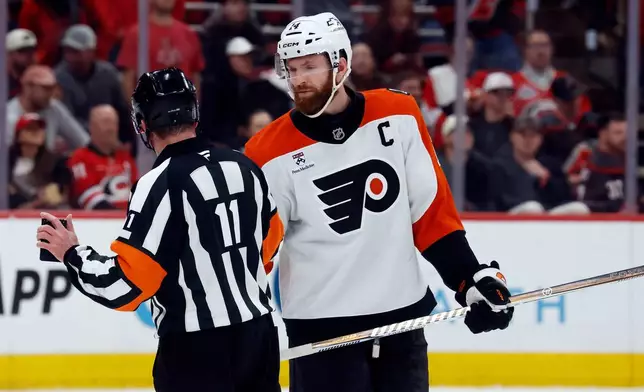Philadelphia Flyers' Sean Couturier, right, talks with referee Kelly Sutherland (11) during the third period of Game 1 of an NHL hockey Stanley Cup second-round playoff series against the Carolina Hurricanes in Raleigh, N.C., Saturday, May 2, 2026. (AP Photo/Karl DeBlaker)