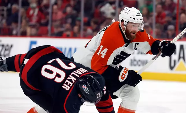 Philadelphia Flyers' Sean Couturier (14) collides with Carolina Hurricanes' Sean Walker (26) during the first period of Game 1 of an NHL hockey Stanley Cup second-round playoff series in Raleigh, N.C., Saturday, May 2, 2026. (AP Photo/Karl DeBlaker)