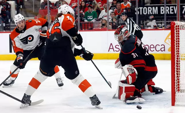 Carolina Hurricanes goaltender Frederik Andersen (31) sends the puck wide of the net with Philadelphia Flyers' Trevor Zegras (46) and Tyson Foerster (71) watching during the first period of Game 1 of an NHL hockey Stanley Cup second-round playoff series in Raleigh, N.C., Saturday, May 2, 2026. (AP Photo/Karl DeBlaker)