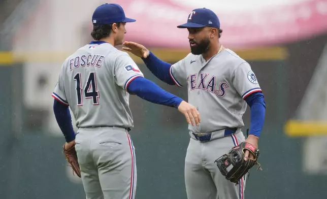 Texas Rangers second baseman Justin Foscue, left, congratulates shortstop Ezequiel Duran after defeating the Colorado Rockies in a baseball game Wednesday, May 20, 2026, in Denver. (AP Photo/David Zalubowski)