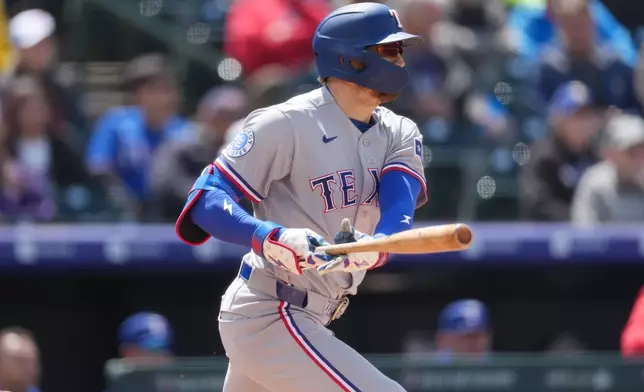 Texas Rangers' Brandon Nimmo singles off of Colorado Rockies starting pitcher Kyle Freeland in the fifth inning of a baseball game Wednesday, May 20, 2026, in Denver. (AP Photo/David Zalubowski)