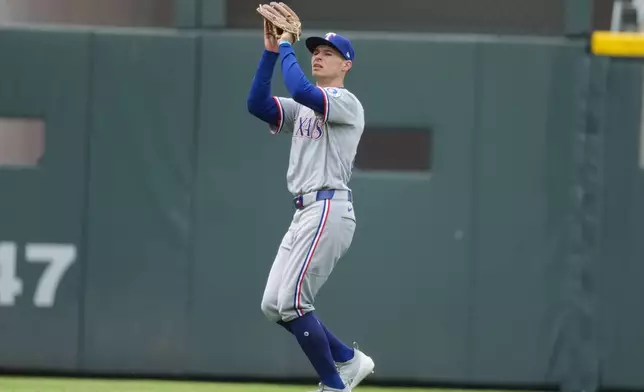 Texas Rangers left fielder Michael Helman pulls in a fly ball off the bat of Colorado Rockies' Jake McCarthy in the seventh inning of a baseball game Wednesday, May 20, 2026, in Denver. (AP Photo/David Zalubowski)