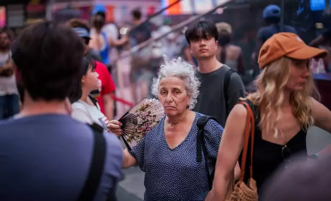 A person uses a fan as they wait in line to purchase Broadway tickets in Times Square, during a heat advisory in New York, Tuesday, May 19, 2026. (AP Photo/Adam Gray)