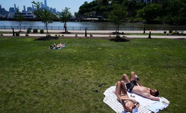 People lay out in the sun in front of the New York City skyline in Hoboken, N.J., Wednesday, May 20, 2026. (AP Photo/Seth Wenig)