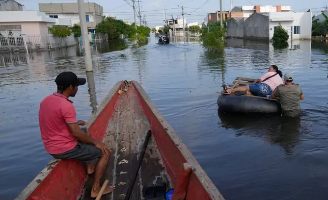 FILE - Residents wade through a flooded neighborhood in Monteria, Colombia, Feb. 10, 2026. (AP Photo/Fernando Vergara, File)