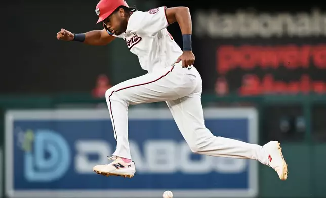 Washington Nationals' James Wood leaps a over a ground ball on his way to second base during the first inning of a baseball game against the New York Mets, Tuesday, May 19, 2026, in Washington. (AP Photo/John McDonnell)