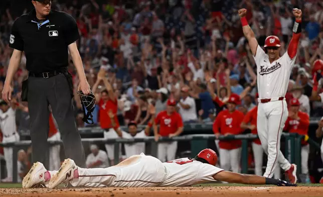 Washington Nationals' Drew Millas, right, celebrates as the Nationals' James Wood slides into home on a inside the park grand slam home run during the second inning of a baseball game against the New York Mets, Tuesday, May 19, 2026, in Washington. (AP Photo/John McDonnell)