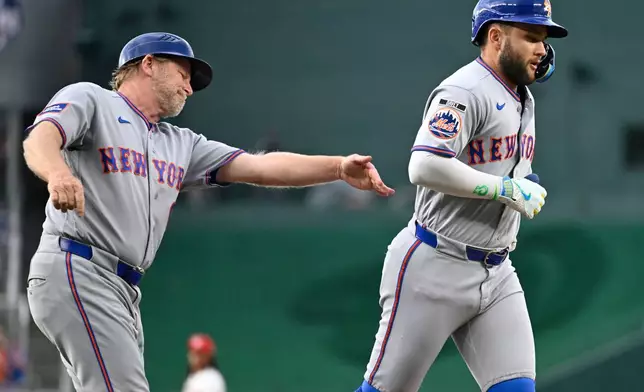 New York Mets third base coach Tim Leiper, left, congratulates Bo Bichette on a two run home run during the first inning of a baseball game against the Washington Nationals, Tuesday, May 19, 2026, in Washington. (AP Photo/John McDonnell)